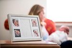 Baby hand and footprint kit packaging displaying included wooden picture frame and stamp accessories.