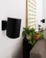 Sanus black speaker mounts installed as a surround sound stereo pair on a living room wall