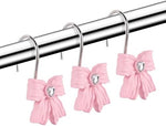 Close up of a pink resin bow curtain ring installed on a metallic shower rod.