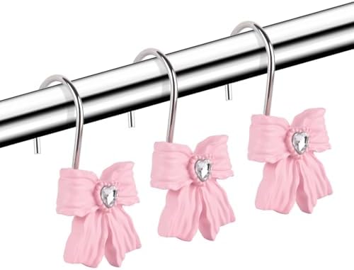 Close up of a pink resin bow curtain ring installed on a metallic shower rod.
