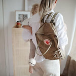 Mushie Shifting Sand pacifier holder case hanging elegantly on a modern diaper bag