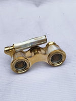 Compact generic brass opera glasses folded down demonstrating its portable size alongside a protective velvet storage case.