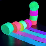Four rolls of UV reactive fluorescent neon paper streamers glowing brightly under a blacklight source