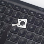 Logitech MX Keys compatible mechanical support brackets displayed alongside repair tweezers on a neutral background