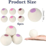 Six white pure New Zealand wool laundry spheres displayed on a natural wooden surface