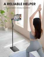 SteelStorm universal tablet stand being adjusted by a user in a modern home living room setting.