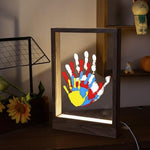 DIY keepsake memory frame with layered colorful family handprints