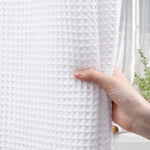 Washable white waffle texture fabric curtain installed over bathtub