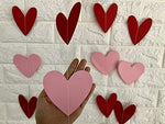 Eco friendly paper heart decorations hung vertically against a living room wall