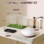 Clear acrylic display case with green turf base protecting a personalized baby handprint football