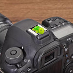 Side profile of a DSLR camera equipped with a unique tortoise hot shoe protector cap