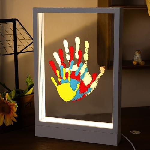 White wooden keepsake frame showing stacked transparent sheets of colorful family handprints