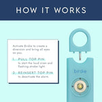 Shes Birdie safety alarm keychain attached to a womans handbag