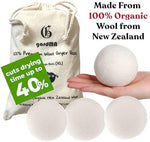Four extra large reusable wool dryer balls arranged together on a laundry surface