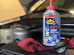 Rislone ZDDP engine oil additive bottle next to engine components