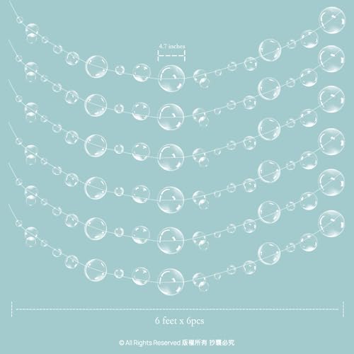 Semi transparent floating bubble streamers draped across a decorated birthday party table setup