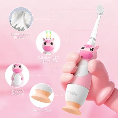 Pink YUNCHI unicorn electric toothbrush being held by a child for scale.