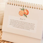Mulberry Lane Co. weekly pregnancy tracker open to a page showing food-inspired baby size comparisons.