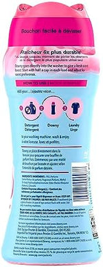Downy laundry scent beads pouring from cap into washing machine drum