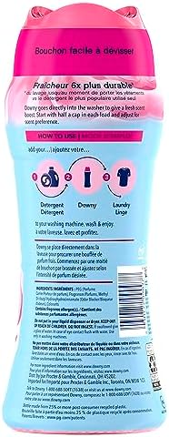 Downy laundry scent beads pouring from cap into washing machine drum