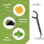 Close up of charcoal infused black dental floss thread on an eco friendly bamboo flosser handle