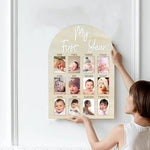 Baby first year photo display board showcasing twelve month photo slots on a nursery wall.