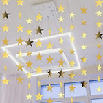 Spakon reusable shimmer paper star decorations hanging vertically on a living room wall