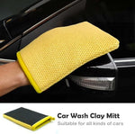 Rinsing a reusable car detailing clay mitt with water during an automotive wash sequence.