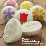 Extra large natural wool fabric softener balls with embroidered flower detail next to storage pouch
