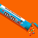 Bite-sized mini milk chocolates poured out of the plastic tube container on a flat surface.