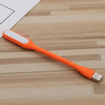 Generic flexible orange USB mini night light front view plugged into a laptop keyboard