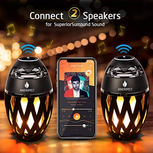 ANERIMST flame torch lantern speaker hanging from a tree branch showcasing the portable metal hook design.