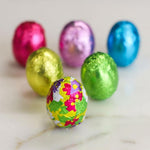 Premium imported USA chocolate mini eggs spread out to show the variety of decorative foil colors.
