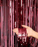 Xo Fetti birthday celebration setup featuring wine colored tinsel fringe behind a dessert table