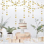 Elegant white and gold heart banner hanging against a neutral wall backdrop for an engagement ceremony.