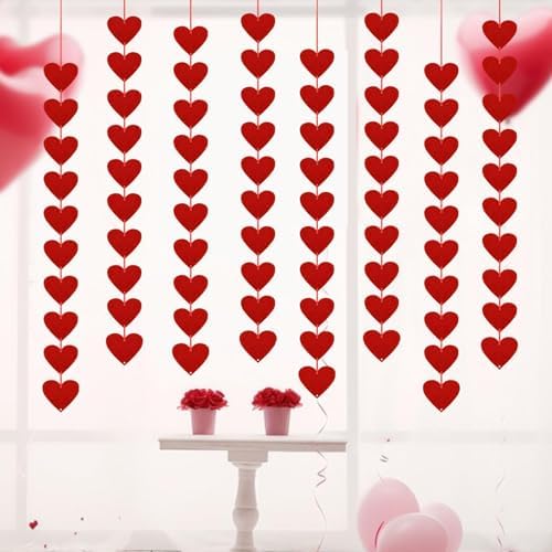 Romantic bedroom setup featuring red heart hanging strings draped over a window frame.