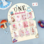 HarpandTimbrel Alice in Wonderland themed first birthday milestone sign displayed on a decorative celebration table.