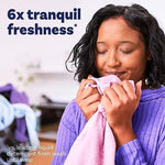 Freshly washed household linens next to a bottle of Downy Infusions Calm.