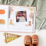Lucy Darling luxury milestone journal opened to show the guided prompt pages and dedicated photo album spaces.