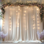 Two panels of ivory fabric drapes hanging beautifully on an event arch stand
