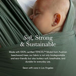 Ergonomic seating position of a toddler nestled securely inside the green Basil sling wrap.