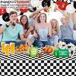 Full setup of racing themed birthday party supplies featuring checkered plastic tablecloths.