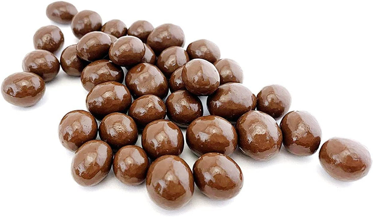 Premium imported chocolate coffee dragees spilled out of packaging close up view.