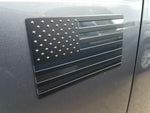 Close-up of matte black and satin chrome American flag badge surface texture