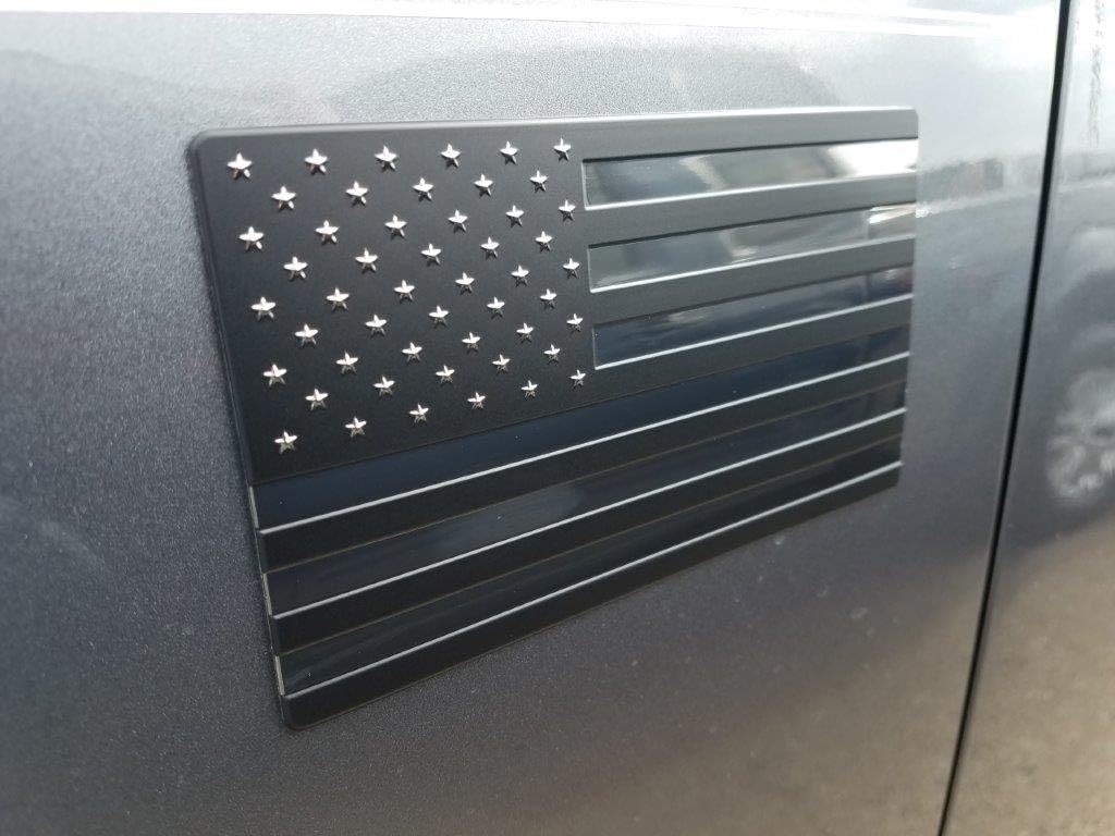 Close-up of matte black and satin chrome American flag badge surface texture