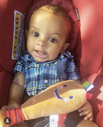 Infant holding the soft plush developmental baseball bat showing its compact size for tiny hands.