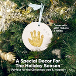 Completed personalized baby handprint ornament with gold paint highlights hanging on a holiday tree