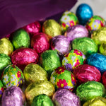 Unwrapped solid milk chocolate mini egg showcasing the smooth gourmet texture and detailed shape.