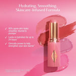 Applying Charlotte Tilbury Unreal multi use blush balm to the cheekbones.