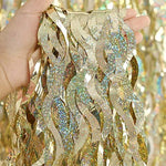 Three pack wavy shape shiny metallic tinsel curtains hanging on a party wall.